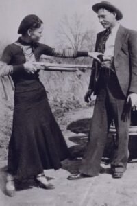 Bonnie Parker jokingly pointing shotgun at Clyde Barrow