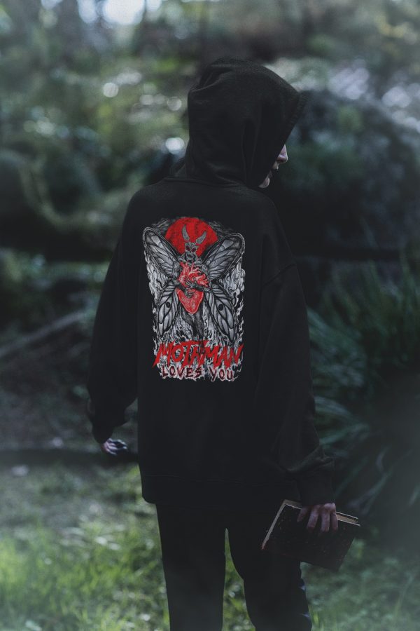 Witchy woman in goth clothing, wearing black mothman loves you hoodie in the woods