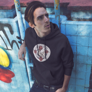 alt style skater punk in dirty commie black hoodie in front of graffiti wall