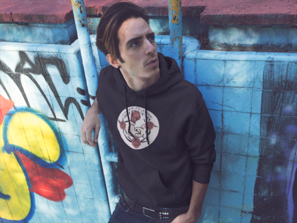 alt style skater punk in dirty commie black hoodie in front of graffiti wall